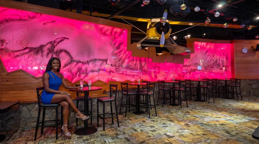 Woman at a high table by the glowing river mural