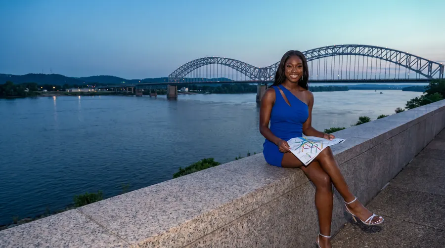 Woman on a granite wall with a map, bridge behind